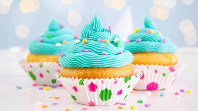 vanilla-and-buttercream-cupcakes-with-blue-icing-and-sprinkles--on-a-blue-background